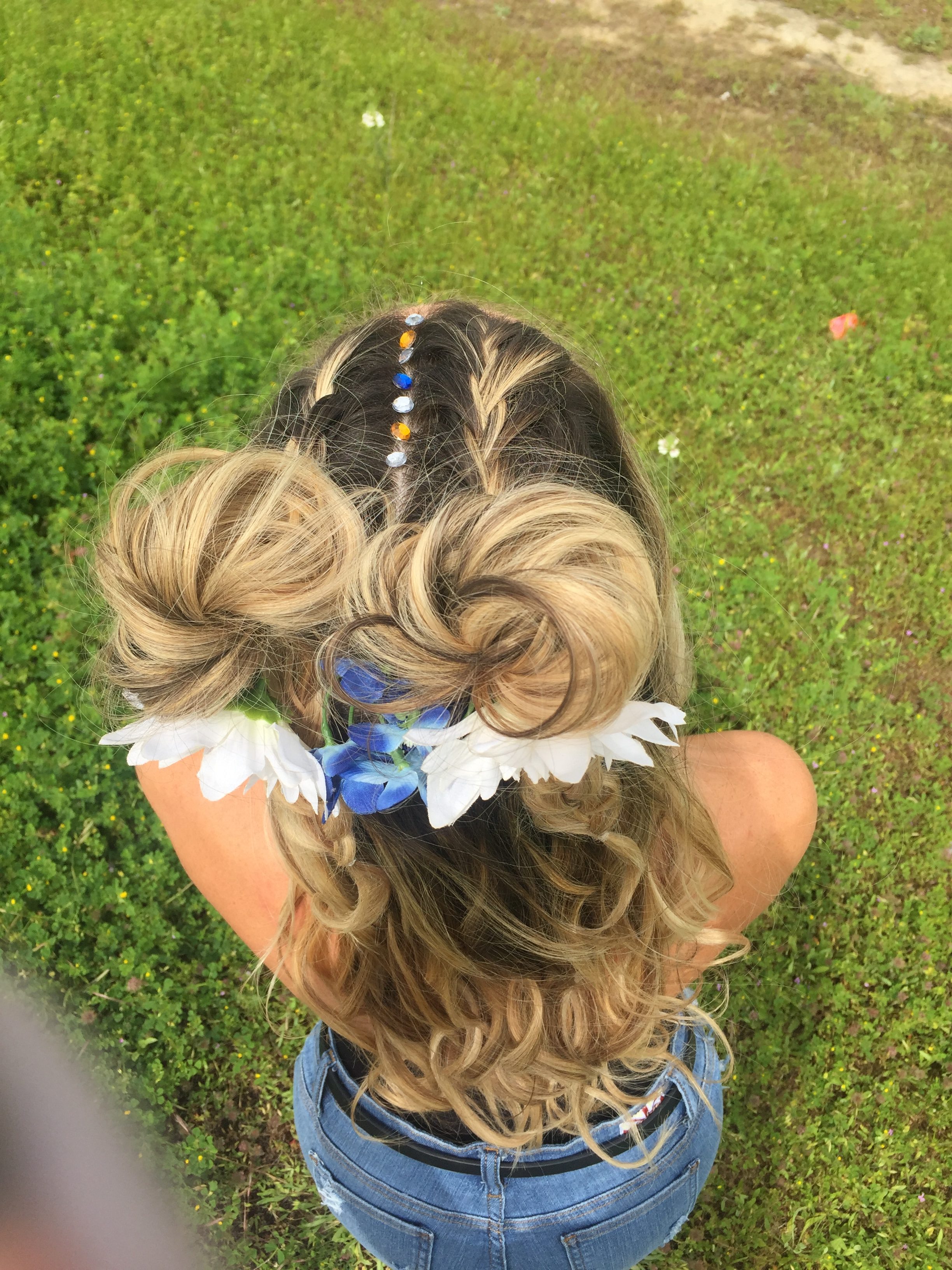 Cute double bun updo with rhinestones along the part and flowers in the buns.