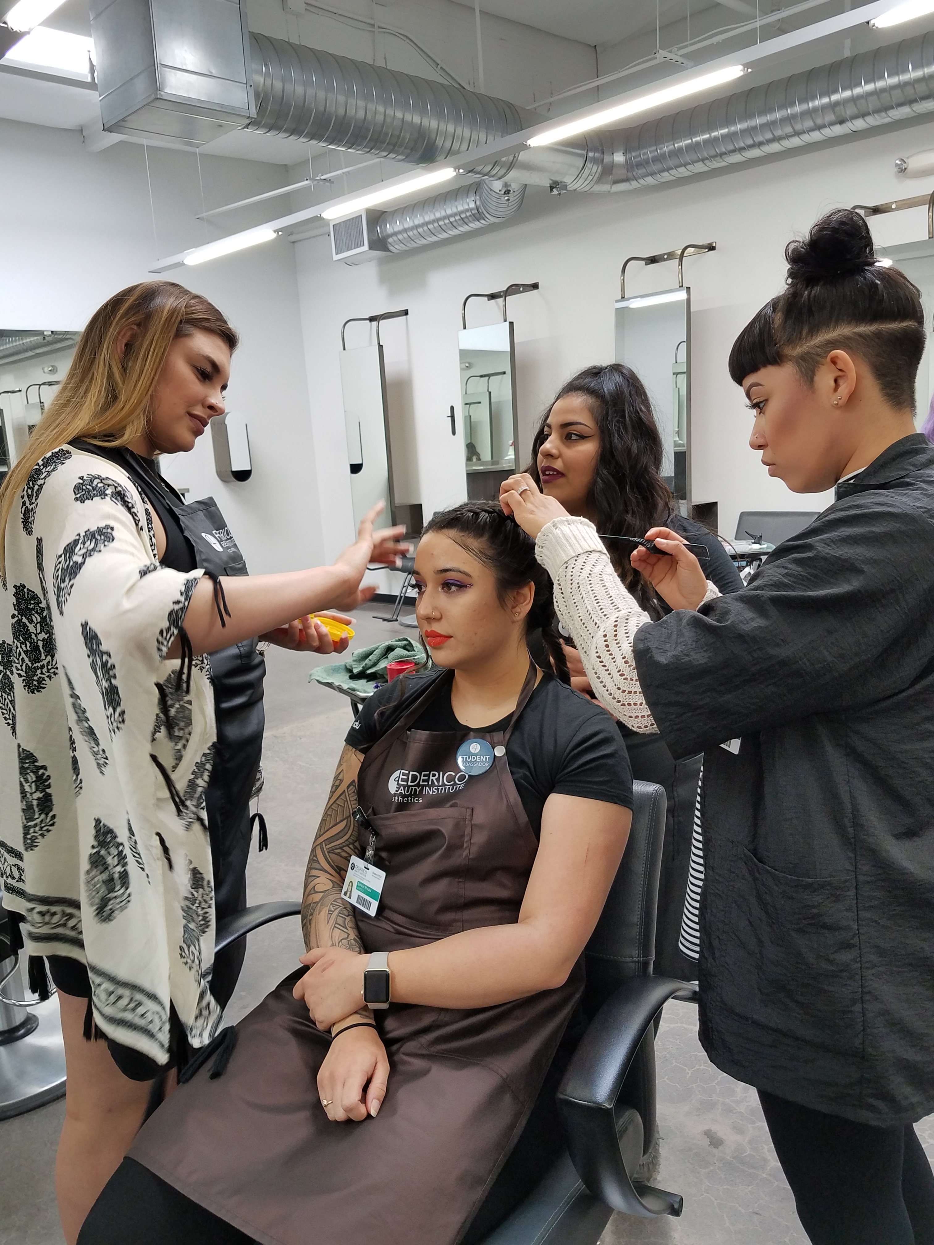 Three people working on the festival hair and makeup of a fellow student.